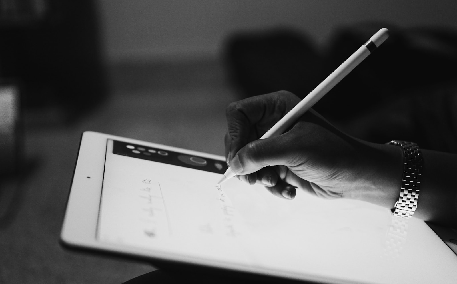A hand writing on an iPad with an Apple Pencil