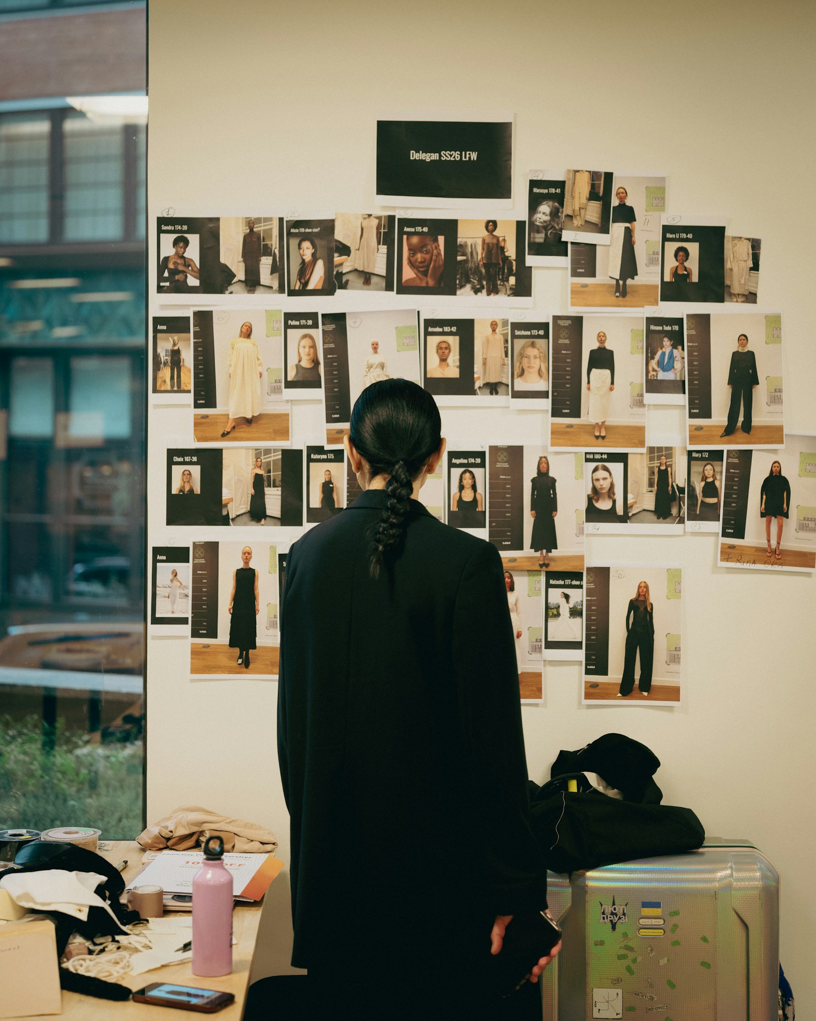 A designer studying a wall covered with fashion references and visual options